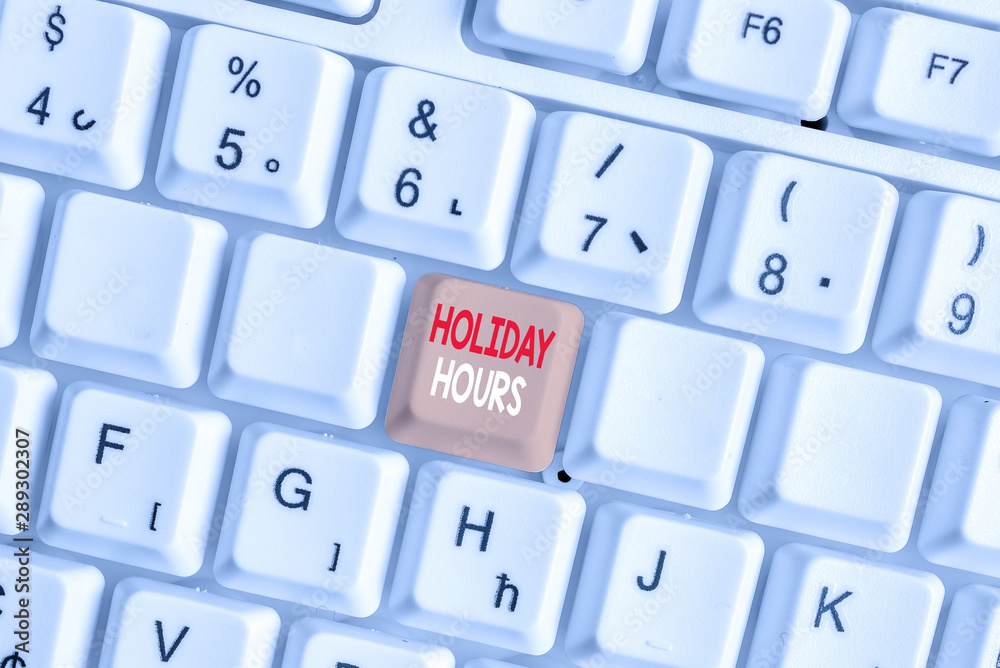 Writing note showing Holiday Hours. Business concept for employee receives twice their normal pay for all hours White pc keyboard with note paper above the white background Writing note showing Holiday Hours. Business concept for employee receives twice their normal pay for all hours White pc keyboard with note paper above the white background