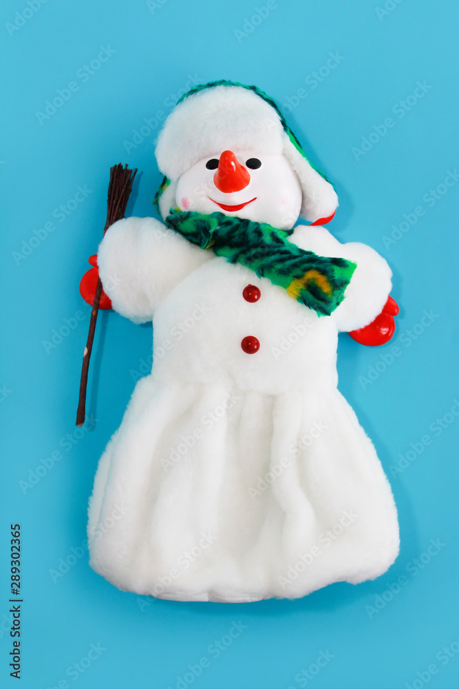 Christmas decorative toy snowman in a white fur coat and hat on blue background for the New Year holiday Christmas decorative toy snowman in a white fur coat and hat on blue background for the New Year holiday