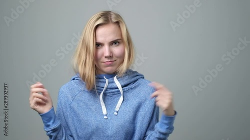Young blonde woman shrugs her shoulders being lost and unsure.