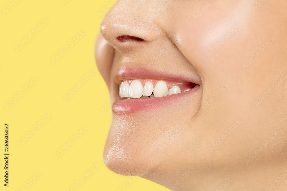 Obraz premium Close up shot of young woman on yellow studio background. Beautiful female model with well-kept skin. Concept of human emotions, facial expression, beauty, healthy lifestyle. Lips, teeth smiling.