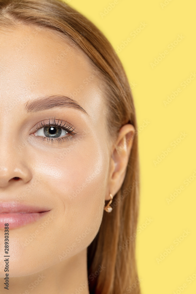 Caucasian young woman's close up shot on yellow studio background. Beautiful female model with perfect well-kept skin. Concept of human emotions, facial expression, beauty, healthy lifestyle.