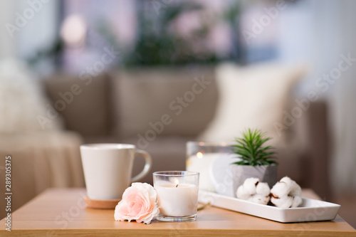 decoration, hygge and cosiness concept - burning fragrance candle and flower bunch on wooden table © Syda Productions