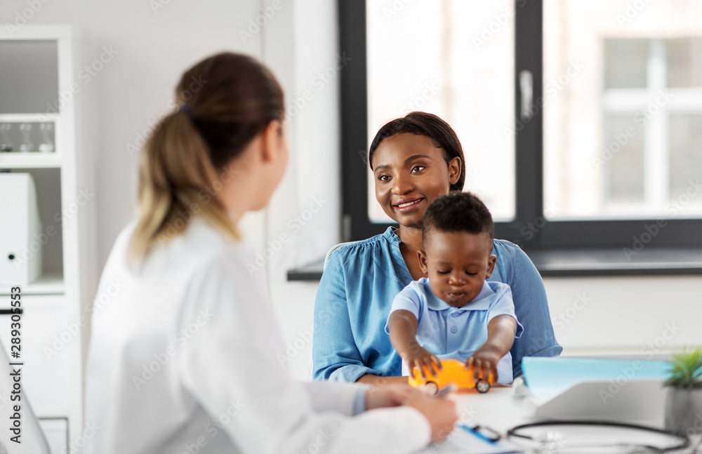 medicine, healthcare and pediatry concept - happy african american mother with baby son and caucasian doctor at clinic medicine, healthcare and pediatry concept - happy african american mother with baby son and caucasian doctor at clinic