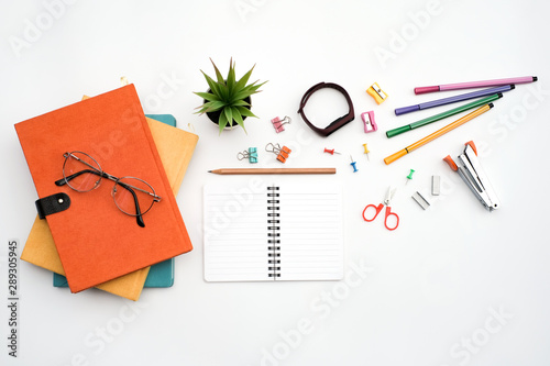 Flat lay black to school and education concept on white table desk with blank notepad and stack of book , green plant and supplies, Top view with copy space, work space