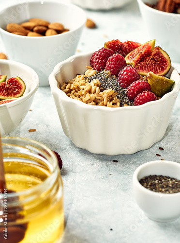 Ingredients for a healthy breakfast, oatmeal with raspberries, figs, pecans, almonds, flax seeds, chia seeds with honey and coffee. Good morning, health concept.