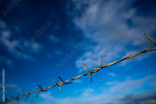 Barbed wire fence along the boundary line The background is blue sky.shallow focus effect.