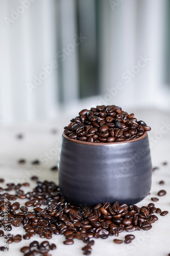 Roasted coffee beans in black cup on marble table