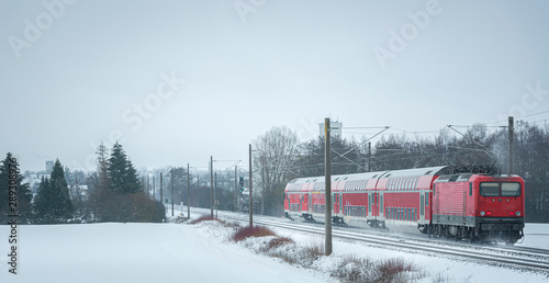 Passengers train in the winter scenery. Train on snowy rail tracks