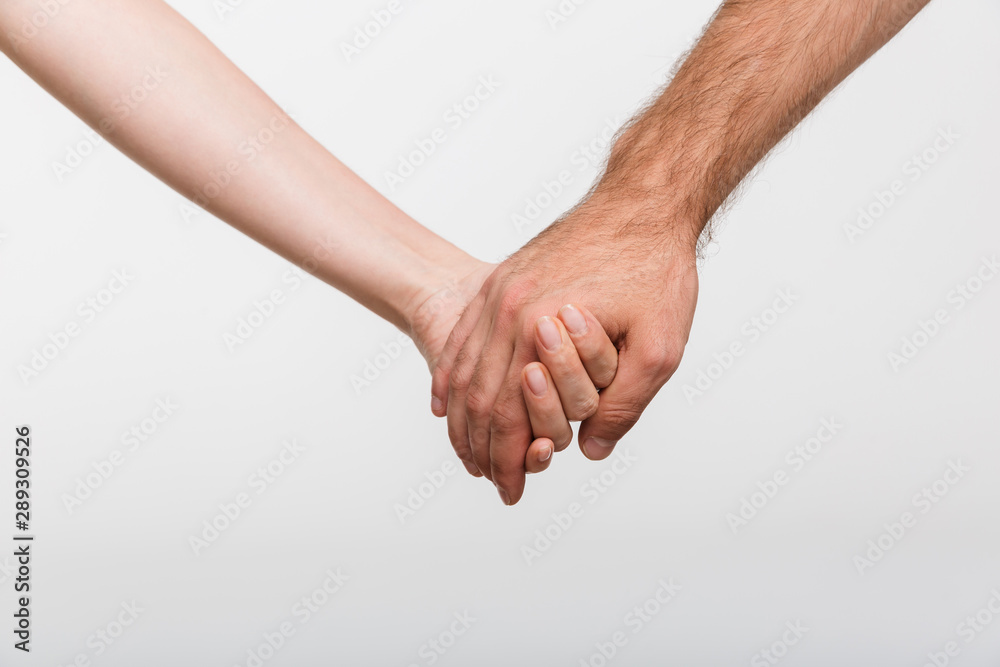 Man and woman holding hands of each other isolated over white wall background. Man and woman holding hands of each other isolated over white wall background.