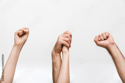 Man and woman holding hands of each other isolated over white wall background make winner gesture.