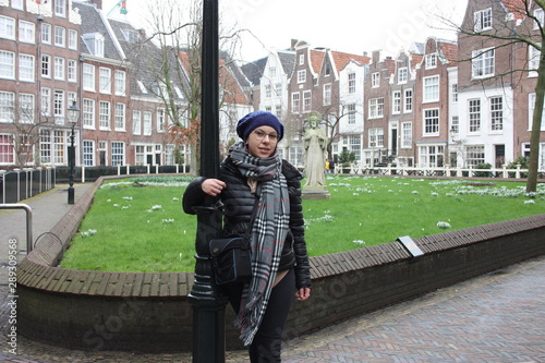 Caucasian tourist girl on field trip in the secret garden of the Beguines in Amsterdam on a winter day