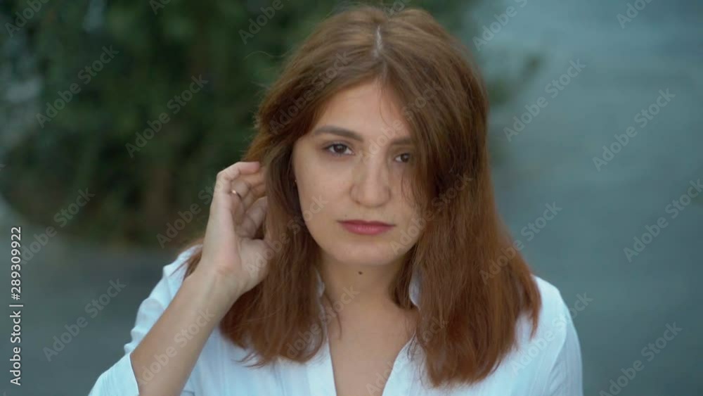 Beautiful girl close-up. Girl posing for the camera in a white shirt in the park. Lush hair. 4k Beautiful girl close-up. Girl posing for the camera in a white shirt in the park. Lush hair. 4k