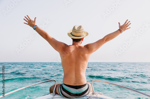 Young man sitting on the bow of the boat enjoying the view at the sea