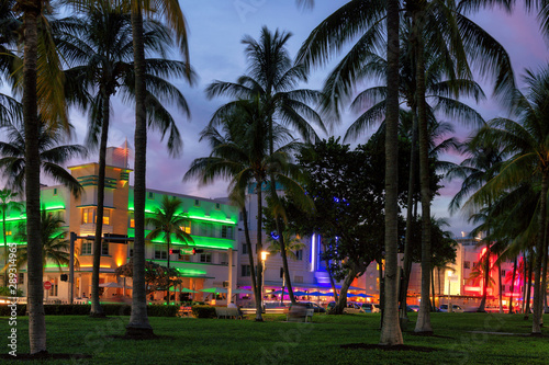 Miami Beach at night, Florida - palm trees, hotels and restaurants at sunset on Ocean Drive.