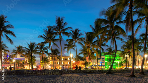 Nightlife in Miami Beach, Florida - palm trees, hotels and restaurants at sunset on Ocean Drive. © lucky-photo