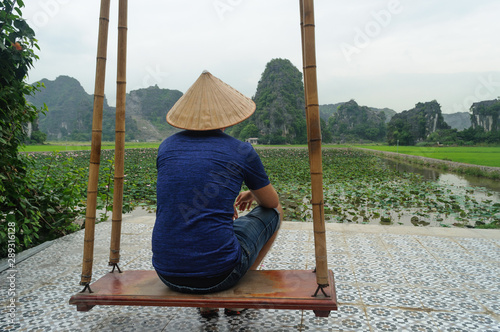 Turista admirando la vista panoramica de las montañas karsticas y campos de arroz desde la cima de Hang Mua Peak en Tamc Coc, provincia de Ninh Minh en Vietnam photo