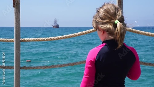 Kleines Mädchen schaut auf das Meer und Piratenschiff