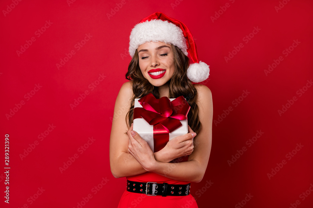 Pretty lady holding big long waited giftbox close to chest wear fluffy mini dress isolated red background Pretty lady holding big long waited giftbox close to chest wear fluffy mini dress isolated red background