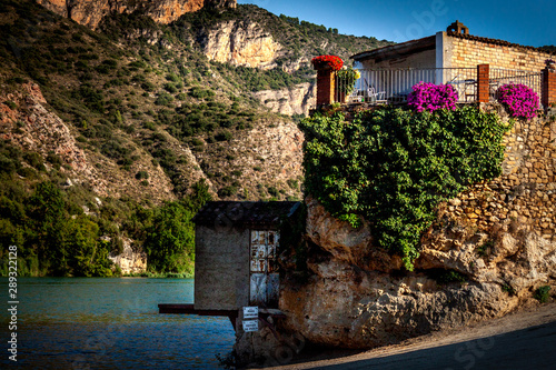 House on the shore with lake and mountain views. Sant Llorenç de Montgai Lake , Segre river, La Noguera, Catalonia photo