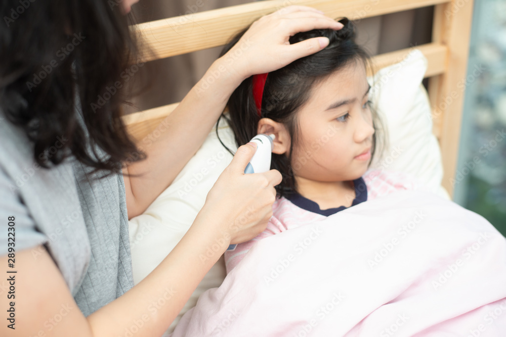 Mother checking body temperature of her daugther with her hand and ear thermometer. Mother checking body temperature of her daugther with her hand and ear thermometer.