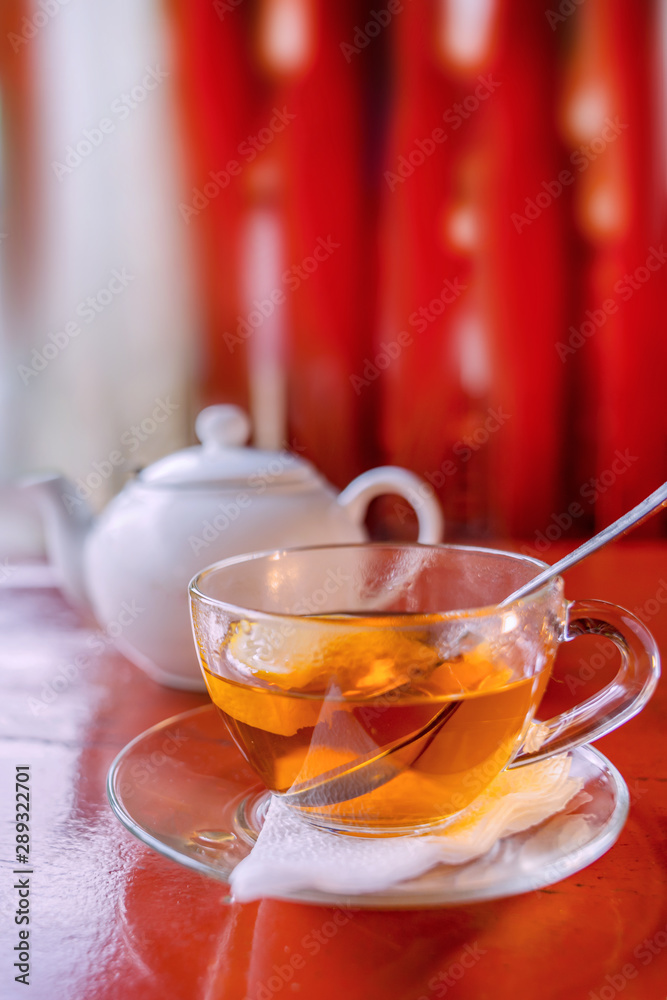 Tea with lemon in a transparent mug on the red table. Tea with lemon in a transparent mug on the red table.