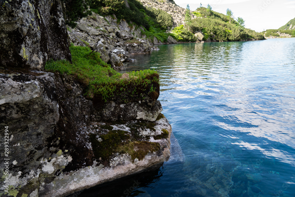Mountain lake, clear turquoise water and big rock Mountain lake, clear turquoise water and big rock