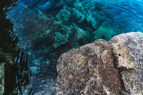 Mountain lake, clear turquoise water and big rock © Vasya