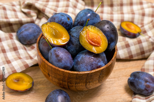 Ripe juicy plums in a wooden bowl. Juicy fruits on a wooden background. Country style.