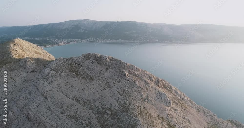 Aerial Drone flight in summer over mountains on the island krk near baska in croatia during sunrise over the sea