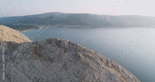 Aerial Drone flight in summer over mountains on the island krk near baska in croatia during sunrise over the sea