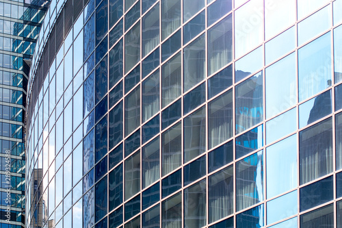 Modern office building with sky reflection on Windows against blue cloudy sky.