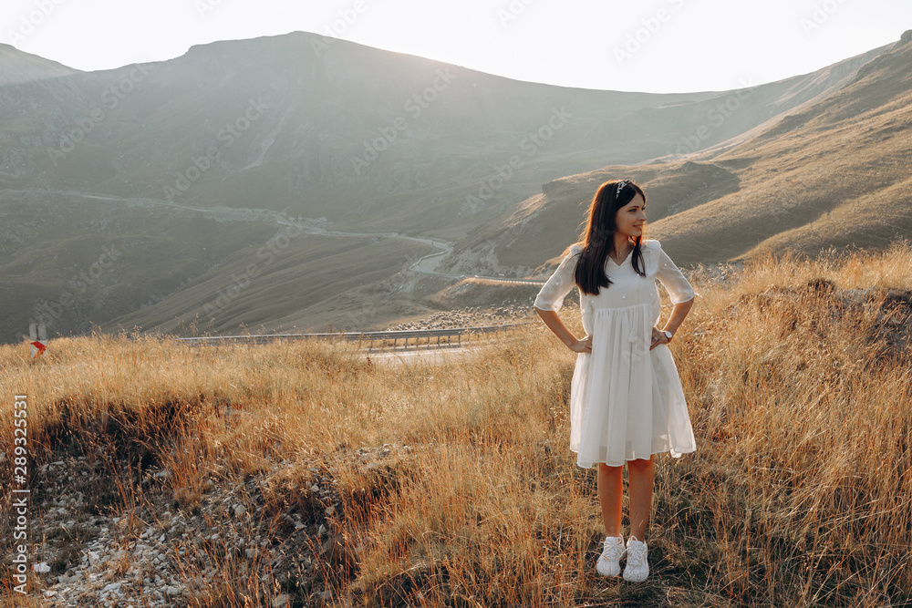 Naklejka premium stylish traveler girl in hat with backpack jumping in mountains. happy hipster woman having fun on top of mountain. space for text. wanderlust and travel concept. atmospheric moment