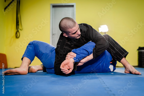 Brazilian Jiu jitsu BJJ jiujitsu training sparring athlete fighter applying kimura shoulder lock submission on his opponent during technique practice