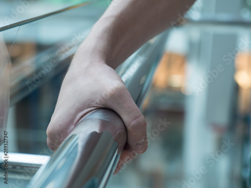 фотографія man holding a hand rail in mall closeup