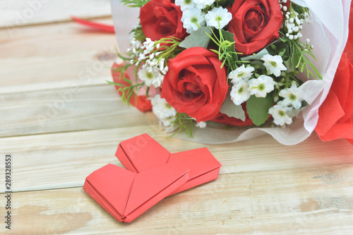 Red roses bouquet and paper hearts shape put on wooden background. Concept for Valentine's day, Birthday or Wedding.