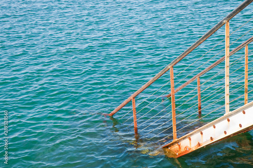 Old metal staircase goes down into the water - concept image with copy space © Francesco Scatena