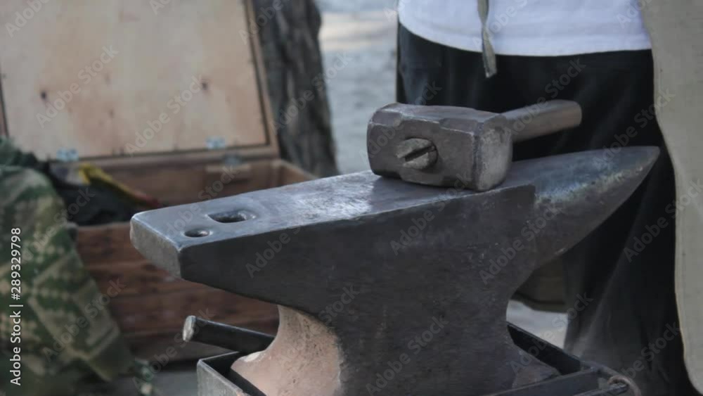 In industry a blacksmith,working hot iron tapping it with a hammer on anvil,and causes hot sparks. Behind the blacksmith a worker using the welding machine. In industry a blacksmith,working hot iron tapping it with a hammer on anvil,and causes hot sparks. Behind the blacksmith a worker using the welding machine.