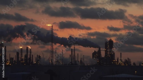 oil refinery factory emits smoke and gas flame after sunset