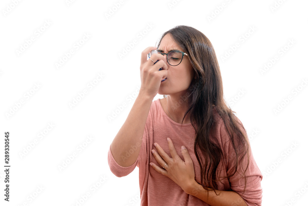 Young caucasian brunette girl with pink shirt suffers from asthma inhaling with an inhaler. isolated in white background. Young caucasian brunette girl with pink shirt suffers from asthma inhaling with an inhaler. isolated in white background.