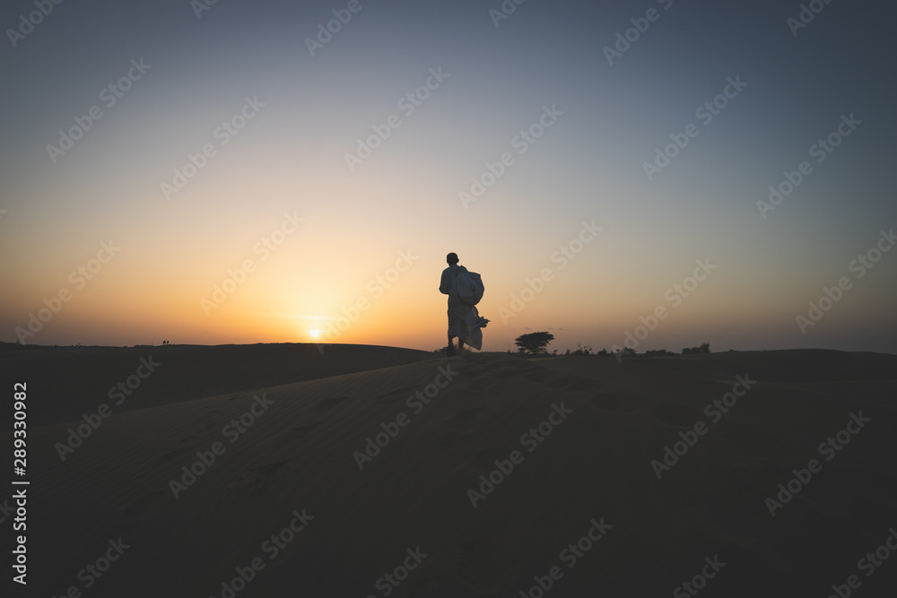 uomo nel deserto al tramonto