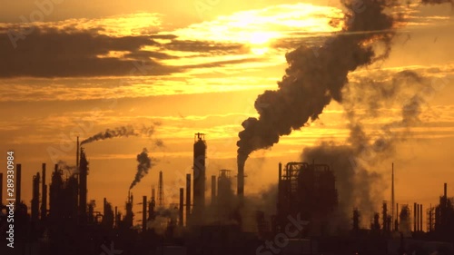 thick smoke clouds spreading in air and covering golden sky