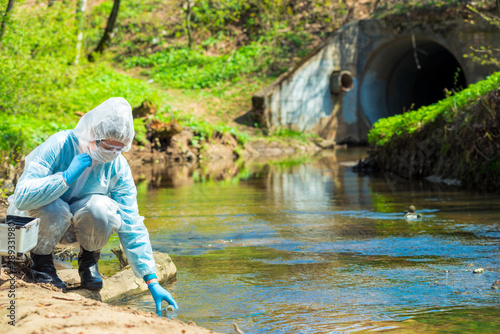 Scientist in protective suite taking water samples from the river