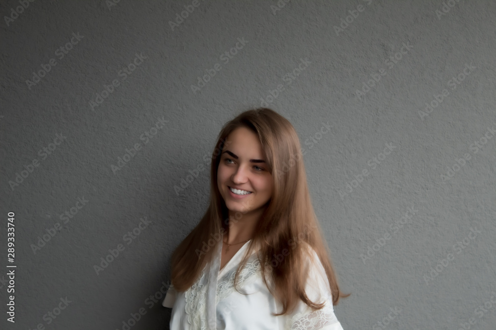 A young, beautiful, blue-eyed girl with a snow-white smile. The girl's look is directed a little aside. Around the girl there is a grey background and а space for text or graphics. A young, beautiful, blue-eyed girl with a snow-white smile. The girl's look is directed a little aside. Around the girl there is a grey background and а space for text or graphics.