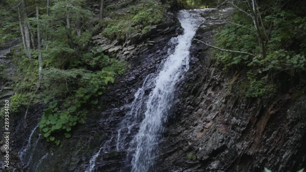 Water falling down in the forest. Huge beautiful waterfall in the forest. Beauty of nature, wild nature. Amazing landscape. Summertime beauty. Top view Water falling down in the forest. Huge beautiful waterfall in the forest. Beauty of nature, wild nature. Amazing landscape. Summertime beauty. Top view