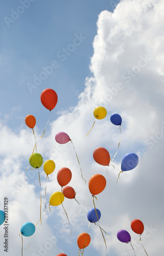 colored balloons flying on the blue sky with clouds during a par