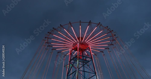 Amusement park red chain carousel with neon lights spinning around photo