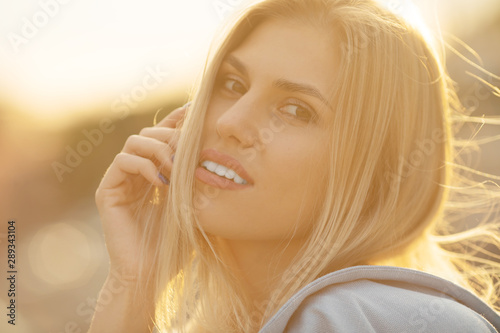Beautiful young blonde woman posing in hot summer sunshine.