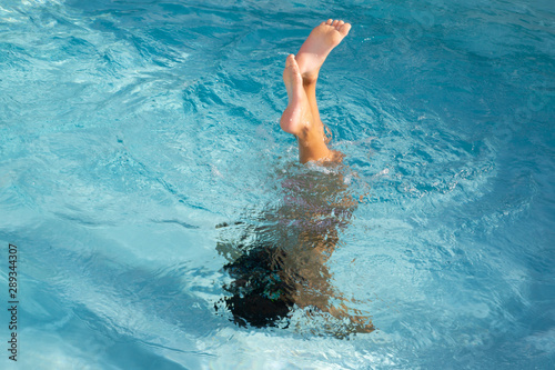 Water splash kid girl boy having fun playing underwater in blue swimming pool on summer vacation