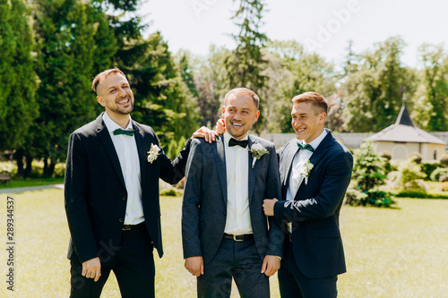 Funny three guys in suits posing in the park.