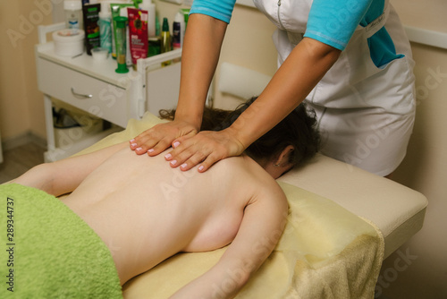 Closeup of masseur's hands doing weight loss massage on woman's back.